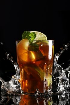 Fresh cold tea with lemon, lime and mint in water splashing