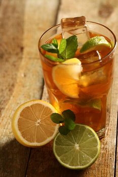 Fresh cold tea with lime, mint and lemon on a wooden surface