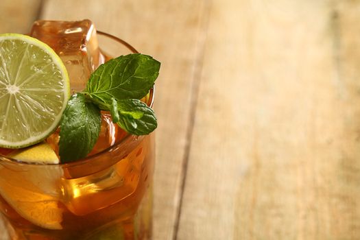 Fresh cold tea with lime, mint and lemon on a wooden surface