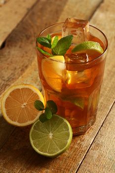 Fresh cold tea with lime, mint and lemon on a wooden surface