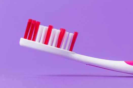 A pink toothbrush on a purple background