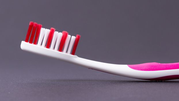 A pink toothbrush on a grey background