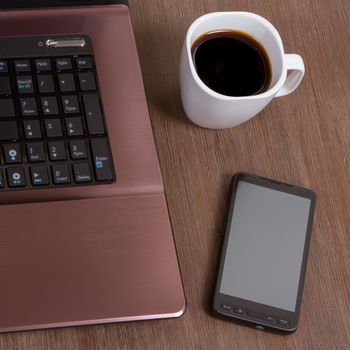 Coffee on wood floor with a laptop and a smartphone