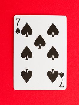 Old playing card (seven) isolated on a red background