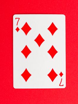 Old playing card (seven) isolated on a red background