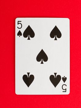 Old playing card (five) isolated on a red background