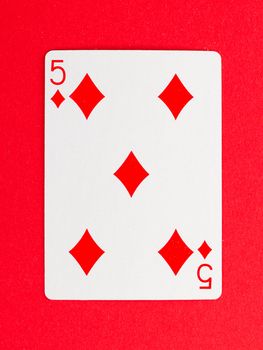 Old playing card (five) isolated on a red background