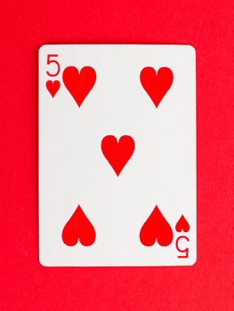 Old playing card (five) isolated on a red background