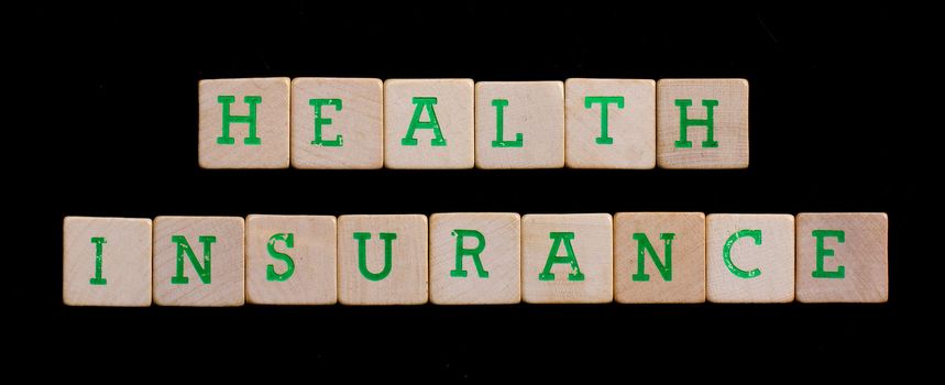 Green letters on old wooden blocks (health, insurance)