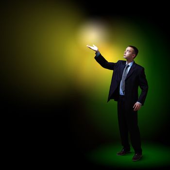 Young successful businessman holding a shining light in his hand as a symbol of success and advancement.