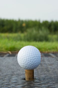 Golf ball with rubber tee with grass in the background