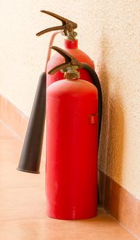 Two red fire extinguishers on a floor