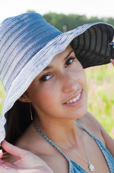 Smiling young woman in denim hat watching you