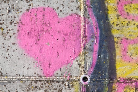 Pink heart graffiti over grunge cement wall