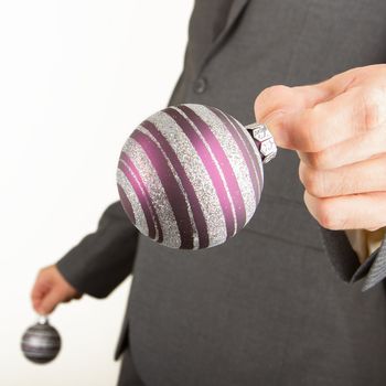 Man in grey suit is holding Christmass balls, isolated