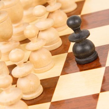 Black pawn on a wooden chessboard, old handcarved set