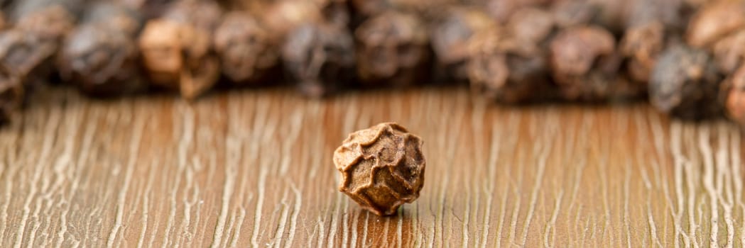 Black pepper isolated on a wooden background
