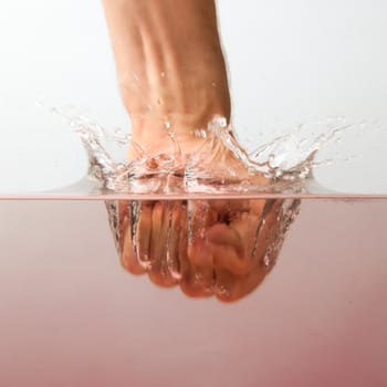 Hand (fist) with splashing red water on a white background