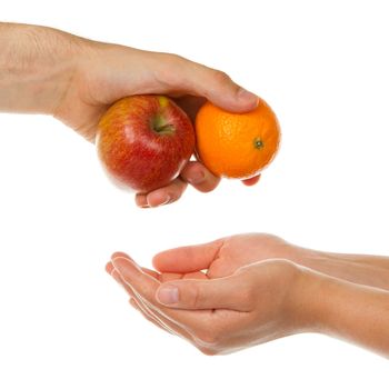Mans hand is giving an apple and an orange to the women hand