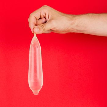 White condom with water in hand, isolated on red background