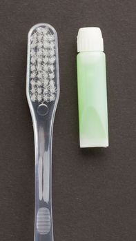 Toothbrush and green toothpaste isolated on a grey background