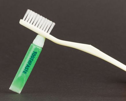 Toothbrush and green toothpaste isolated on a grey background