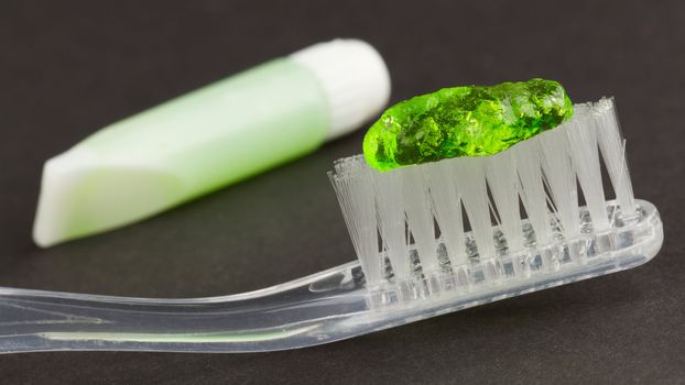 Toothbrush and green toothpaste isolated on a grey background