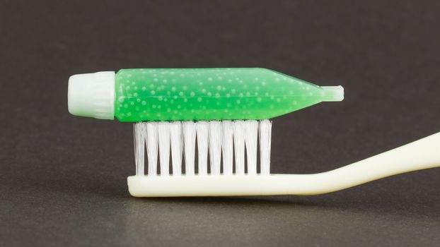 Toothbrush and green toothpaste isolated on a grey background