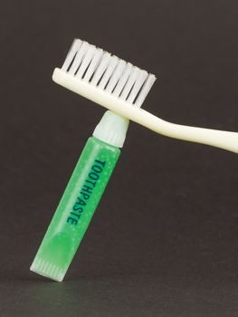 Toothbrush and green toothpaste isolated on a grey background