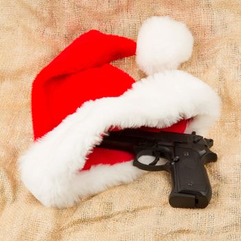 Weapon (firearm) concealed in santas hat, isolated on canvas