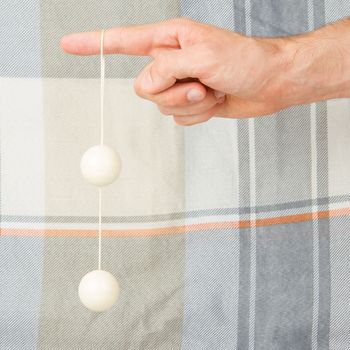Hand holding white vaginal balls, isolated on an old quilt