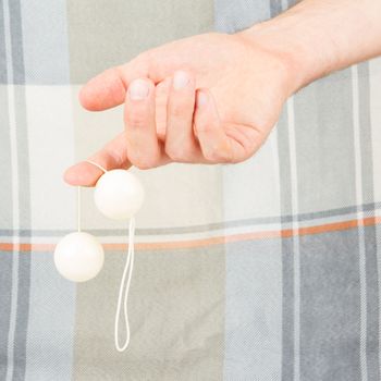 Hand holding white vaginal balls, isolated on an old quilt