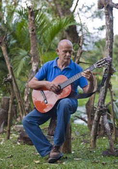 Latino guitar player playing is a tropical setting.