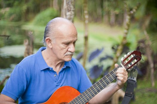 Latin American musician playing a guitar in a park.