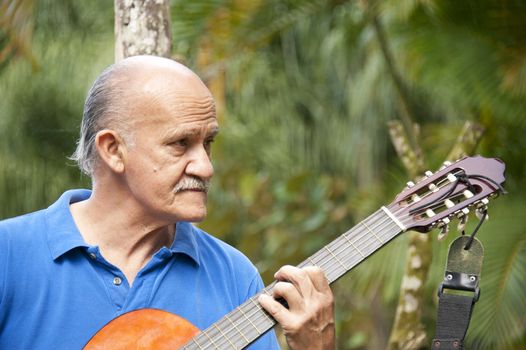 Latin American musician playing a guitar in a park.