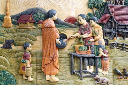 native culture Thai stucco on the temple wall, Thailand, give food offerings to a Buddhist monk