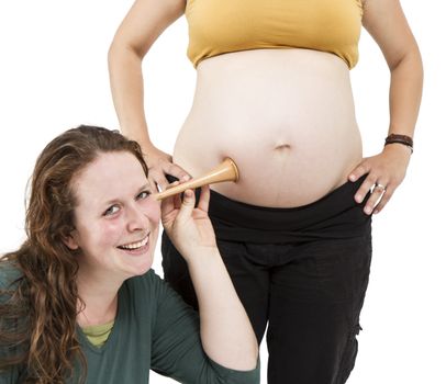 young midwife listening at human belly. pregnant woman standing while midwife is sitting in front. horizontal picture isolated on white