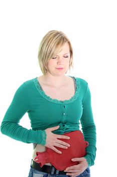 Woman suffering from a stomach ache holding a warm hot-water bottle to her abdomen in an attempt to alleviate the pain isolated on white