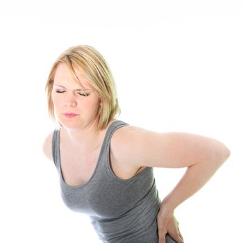 Studio portrait over white of a young woman holding her lower back in obvious pain from a back injury or strain