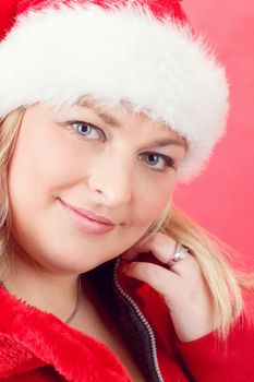 Portrait of joyful pretty woman in red santa claus hat smiling on red background