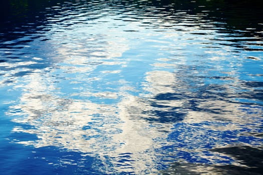 Sky with clouds reflecting in rippled water surface