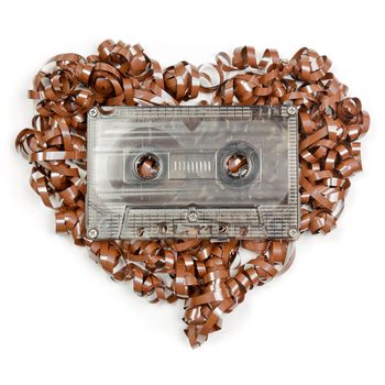 Vintage transparent Compact Cassette with pulled out tape in the shape of heart on white background