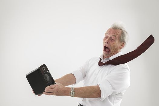 Conceptual studio shot over white of an old man being blasted by a sound wave from an audio speaker