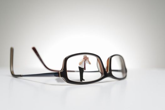 Conceptual photograph of life size glasses and a male model looking through one side of the eyeglasses.