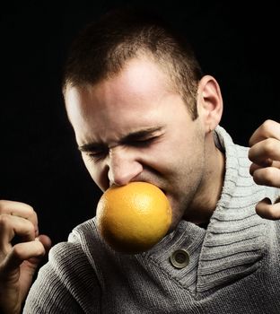 Young man biting a bitter grapefruit