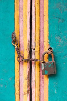 Vintage lock and chain on an old colorful wooden door 