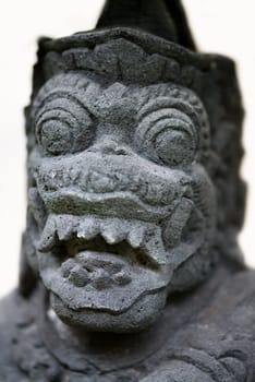 Closeup of traditional Balinese God statue made of volcanic stone, selective focus on eyes