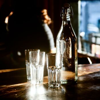 Cold fresh water in old-fashioned bottle with glasses on a cafe table