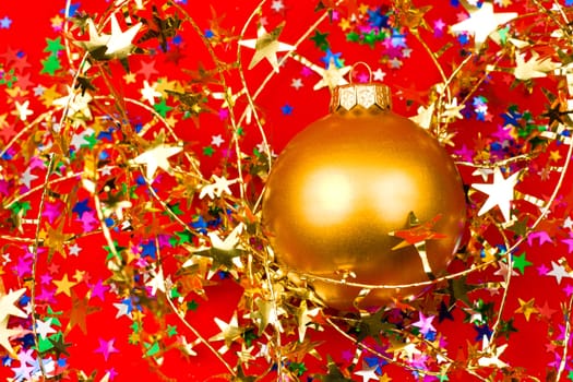 Golden Christmas bauble with star shaped tinsel on red background