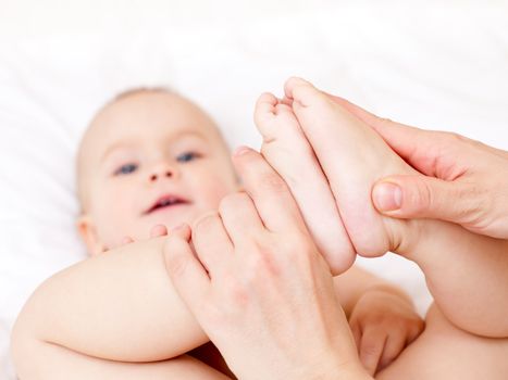 Masseur massaging little baby's feet, shallow focus